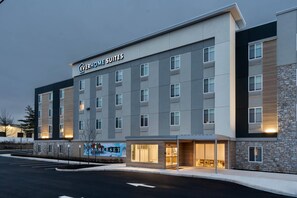 Un edifici d'hotel modern amb la senyalització 'Everhome Suites', diverses finestres i un aparcament.
