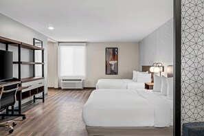Une chambre d’hôtel avec un bureau, deux lits, une télévision et une grande fenêtre.