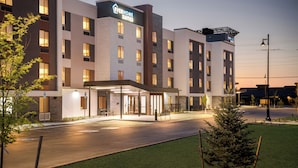 Un hotel moderno con techo plano, varios pisos y una entrada bien iluminada.