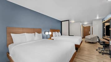 Ein Hotelzimmer mit zwei Betten, einem Schreibtisch, einem Stuhl und einem großen Spiegel.