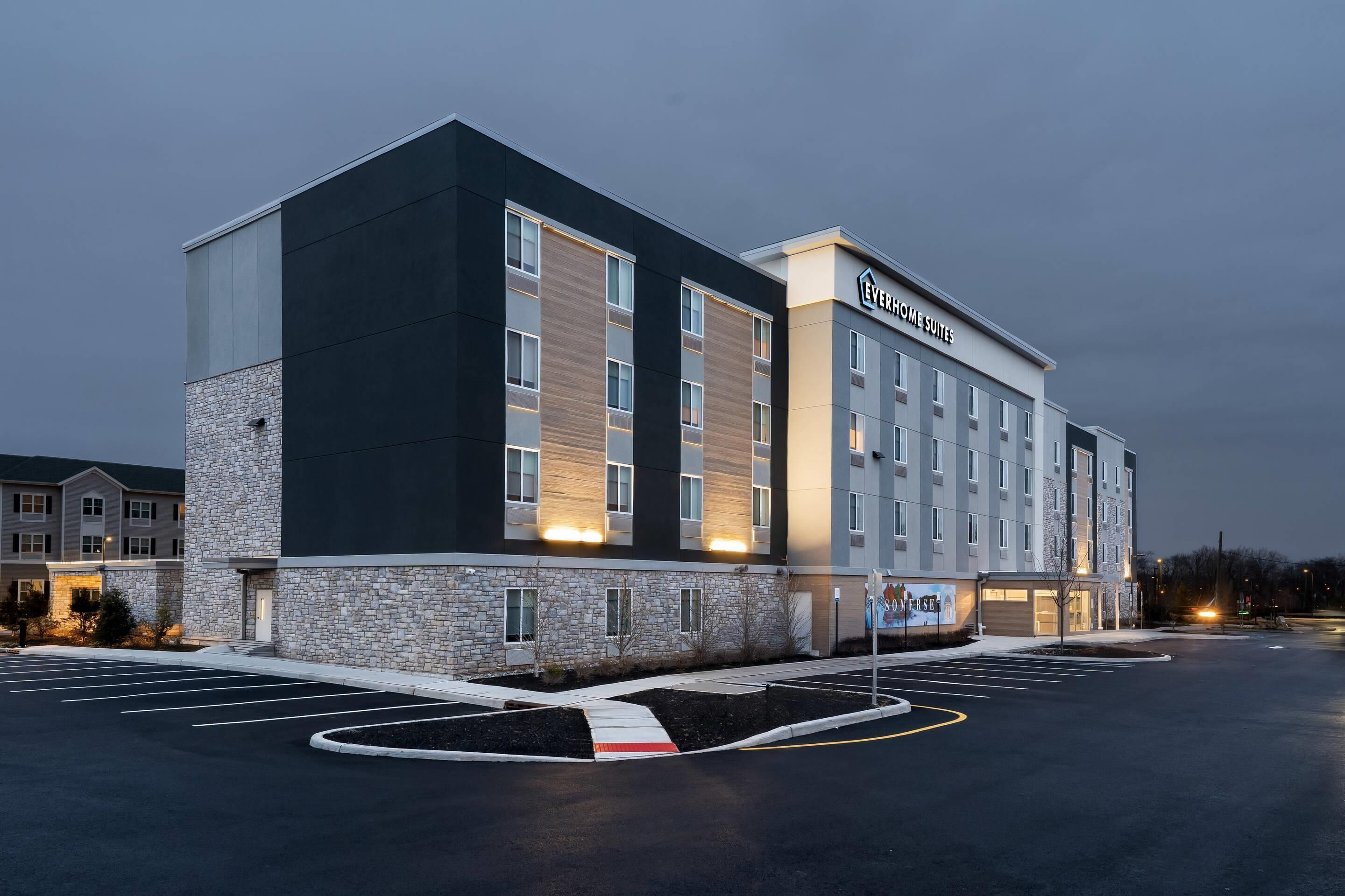 Un hotel de diseño moderno, con fachada de piedra, ventanas amplias y estacionamiento.