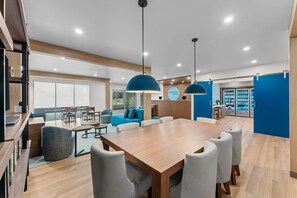 Un vestíbulo de hotel moderno con un mostrador de recepción de madera, una amplia mesa de conferencias y zonas de estar.
