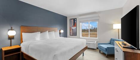 A hotel room with a bed, bedside tables, a TV, a desk, and a window.