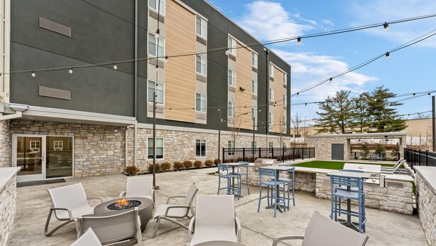 Un patio de hotel con mobiliario exterior, una zona de fogata y un área de barbacoa.