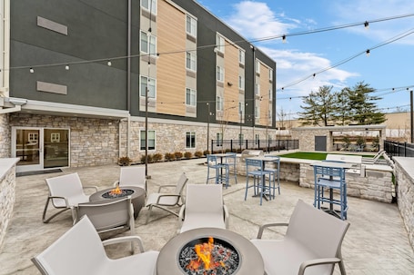 A hotel patio with outdoor seating, a fire pit, and a barbecue area.. Everhome Suites Somerset - South Brunswick by Choice Hotels