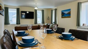 A dining area with a wooden table set for four, surrounded by leather chairs.