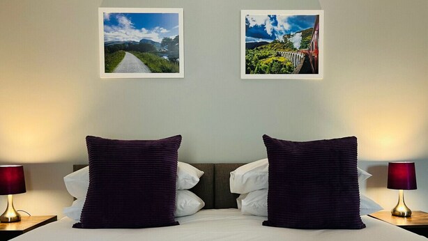 A double bed with two large pillows, a headboard, and two bedside lamps.