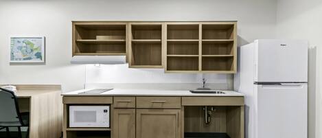 Una cocina compacta con armarios de madera, un microondas integrado y un refrigerador blanco.