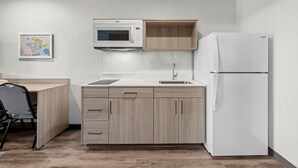 A compact kitchen with a microwave, sink, and refrigerator. - Woodspring Suites Anderson North I-85 (Anderson)