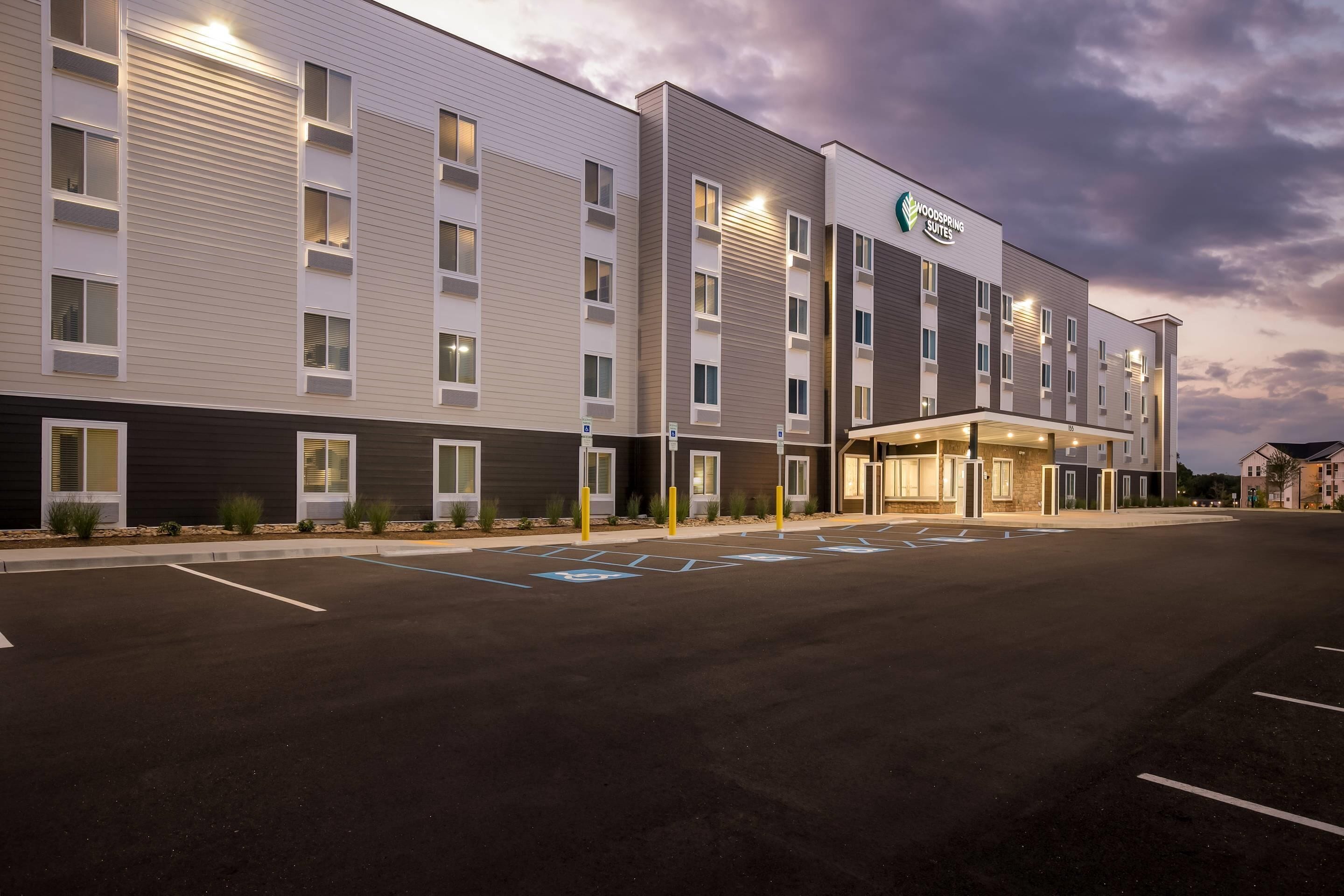 Un hotel de exterior moderno, con varios pisos y un estacionamiento que incluye espacios para discapacitados.