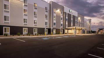 A hotel with a modern exterior, multiple floors, and a parking lot with handicapped spaces.