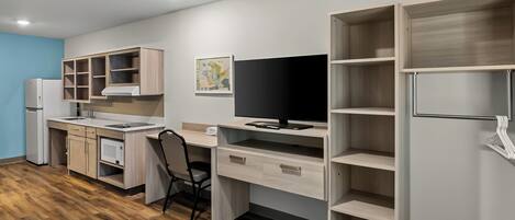 Una cocina moderna con estufa integrada, comedor con una silla y un amplio estante abierto.