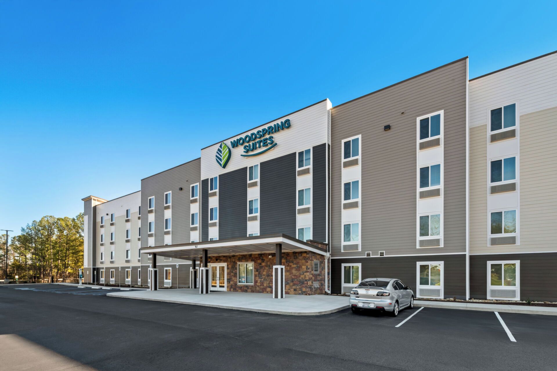 A hotel with a modern design, featuring a large sign with the name 'Woodspring Suites'.