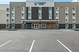 Un hotel moderno con fachada plana, varios balcones y un acceso cubierto.