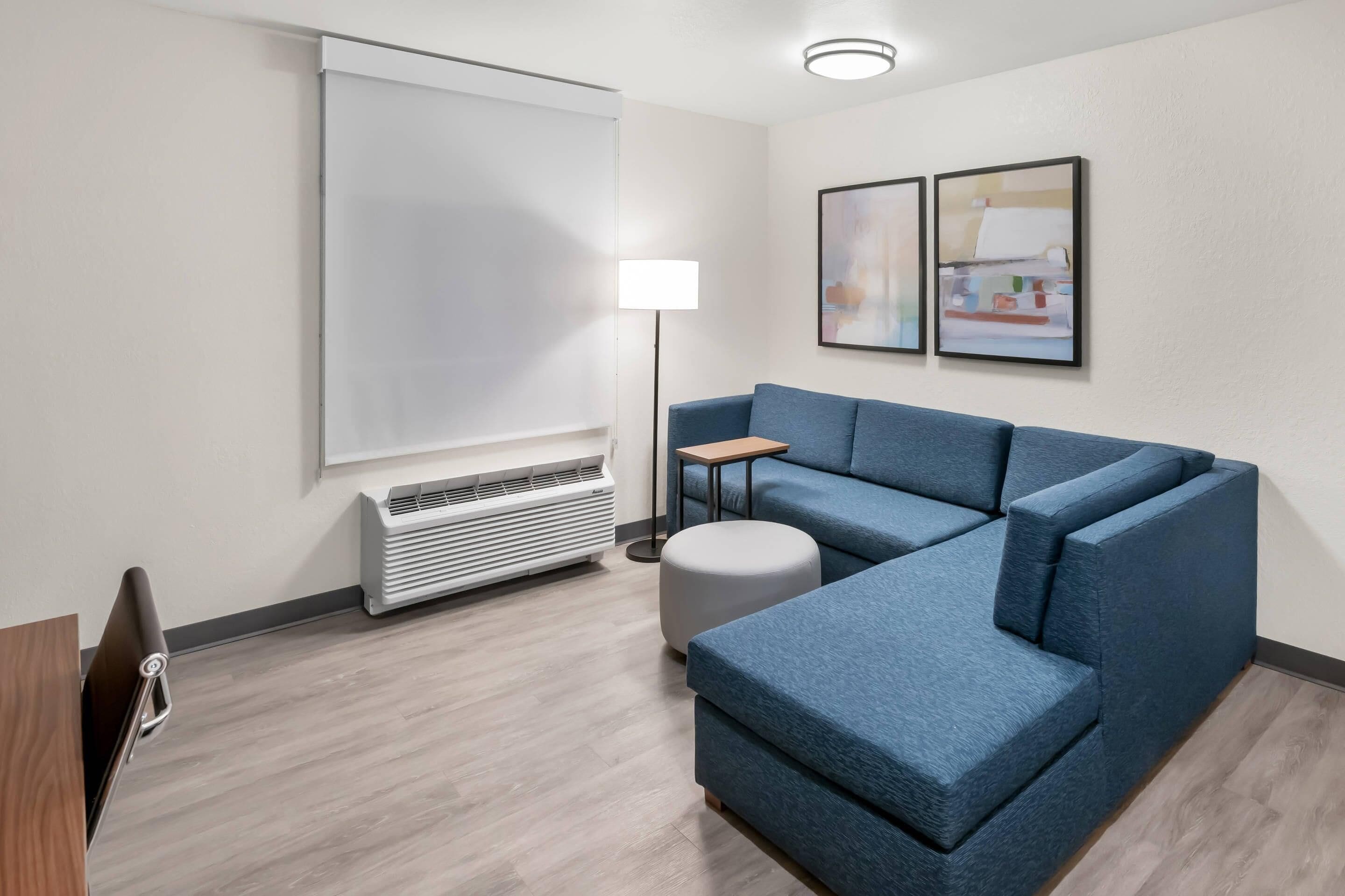 Una habitación moderna con sofá modular, lámpara de pie, televisor de pantalla plana y aire acondicionado instalado en la pared.