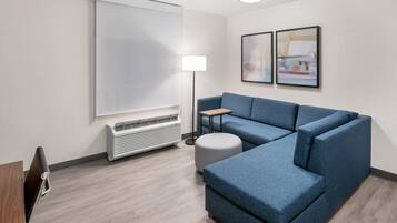 Una habitación moderna con sofá modular, lámpara de pie, televisor de pantalla plana y aire acondicionado instalado en la pared.
