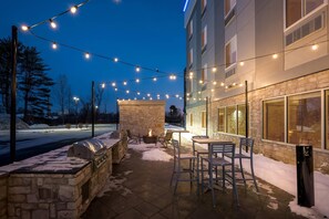 An outdoor patio with stone walls, a barbecue grill, and outdoor seating. - Everhome Suites Portsmouth - Newington by Choice Hotels (Portsmouth)