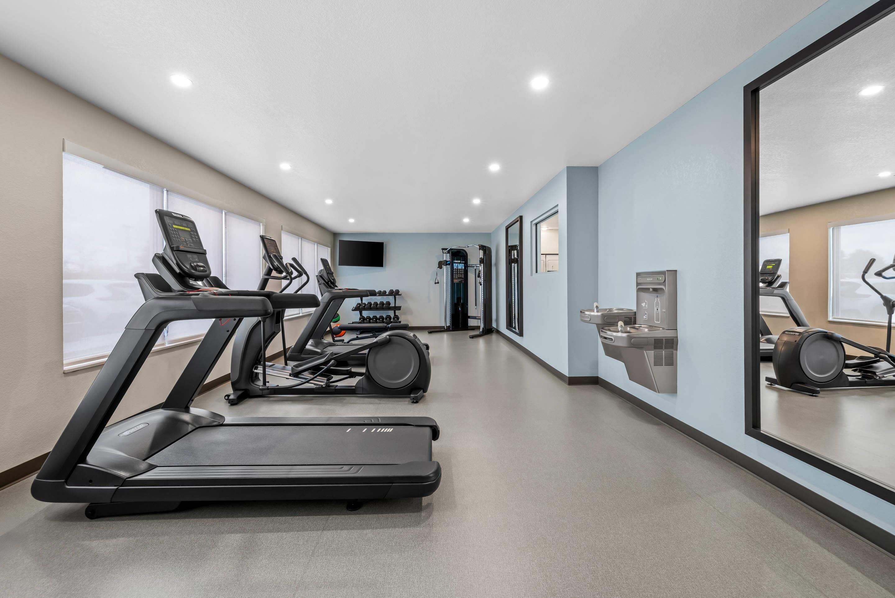 Een moderne sportschool met loopbanden, elliptische trainers en een krachttrainingapparaat.