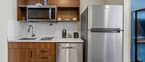 A modern kitchen with a built-in microwave, a stainless steel refrigerator, wooden cabinets, and a dishwasher.