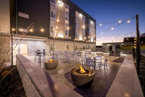 An outdoor patio area with stone walls, fire pits, and outdoor seating. - Everhome Suites Rochester Greece (Rochester)