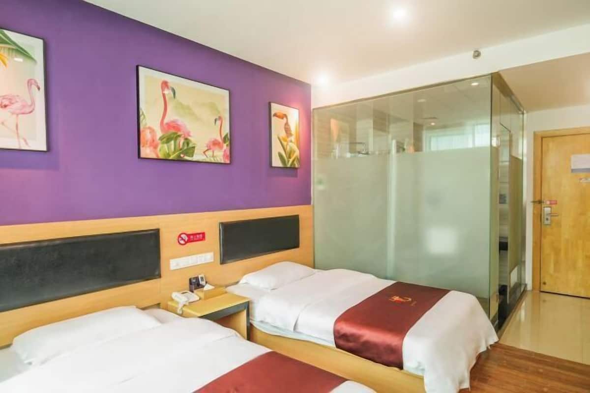 A hotel room with two beds, a glass partition, and artwork on the wall.