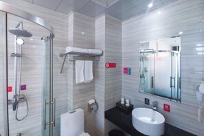 A modern bathroom with a glass-enclosed shower, a white sink, and a large mirror.