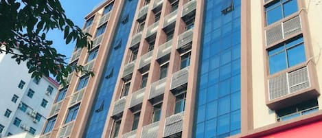 Un immeuble à plusieurs étages, sur lequel on peut voir une enseigne rouge indiquant un commerce.