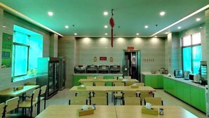A dining area with tables and chairs, a refrigerator, and a microwave on the counter. - Shankee Hotel (Maoming High-Speed Railway Station 1959 Cultural and Creative Pedestrian Street) (Maoming)