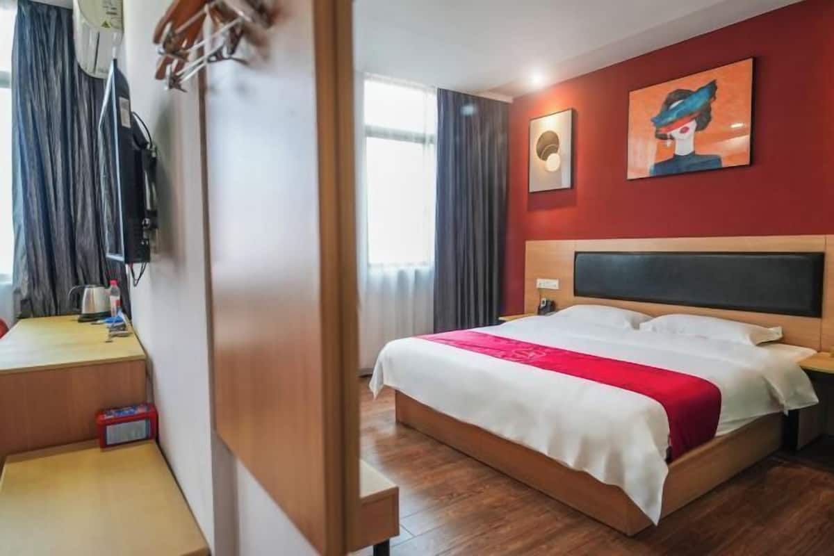 A hotel room with a bed, bedside table, and a television mounted on the wall.