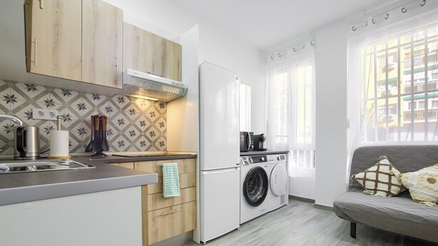 A compact kitchen with a built-in washing machine, a coffee maker, and a sink.