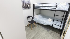 A bunk bed room with a chair, a cityscape painting, and a tiled floor.