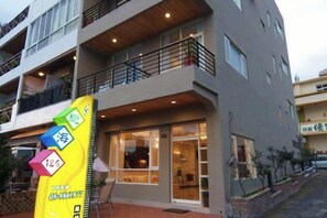 A multi-story building with a ground-level entrance, balconies, and a visible window. - Love Sea 126 House Inn Hostel (Pingtung)