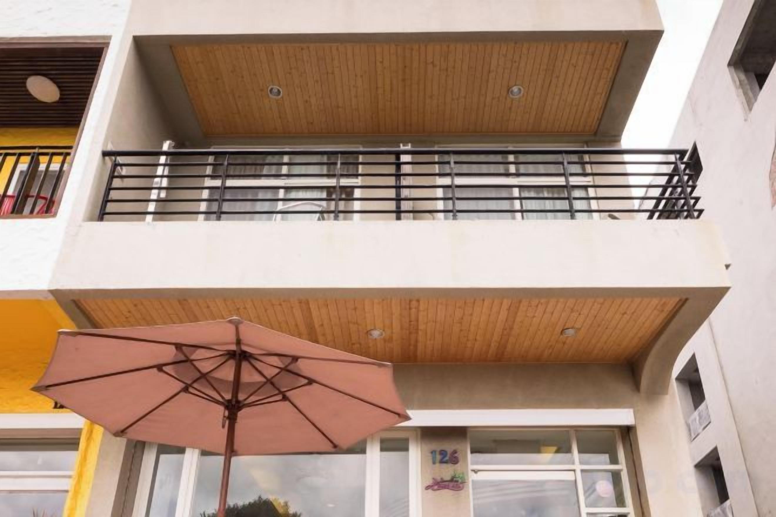 Un edificio de varios pisos con un balcón y una sombrilla.