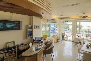 A modern hotel lobby with a curved ceiling, a reception desk, and a dining area with chairs and tables. - Love Sea 126 House Inn Hostel (Pingtung)
