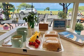 A tray with food and drinks, a framed picture, and a view of the beach. - Love Sea 126 House Inn Hostel (Pingtung)