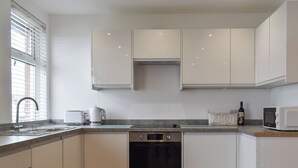 A modern kitchen with white cabinets, a stainless steel oven, and a microwave. - 2 bedroom accommodation in Whitby (Whitby)