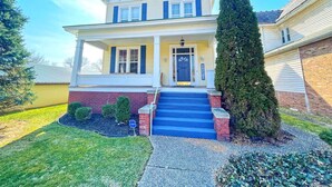 A two-story house with a front porch, a brick foundation, and a well-maintained lawn.