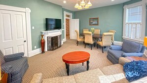 A living room with a fireplace, a television, and a dining area with chairs and a table.