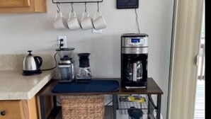 Une cuisine équipée d’une machine à café, d’une bouilloire et de paniers de rangement placés sur un chariot en métal.