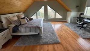 Une chambre avec un plafond en pente, un lit, un bureau et une fenêtre.