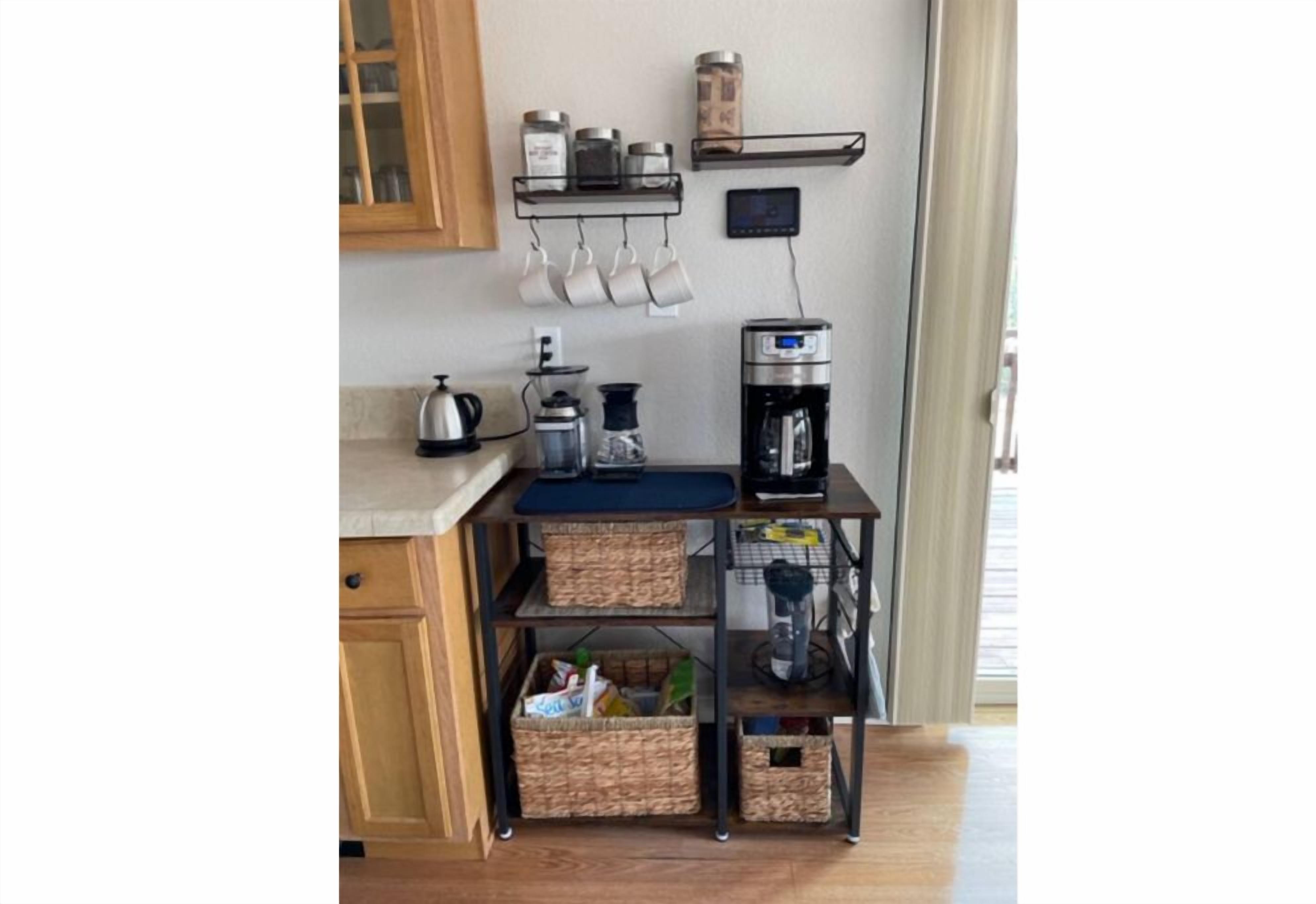 A kitchen with a coffee maker, kettle, and storage baskets on a metal cart.