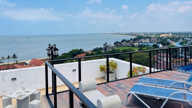 Une terrasse sur le toit offrant une vue sur la mer, un bâtiment blanc et une église au loin.