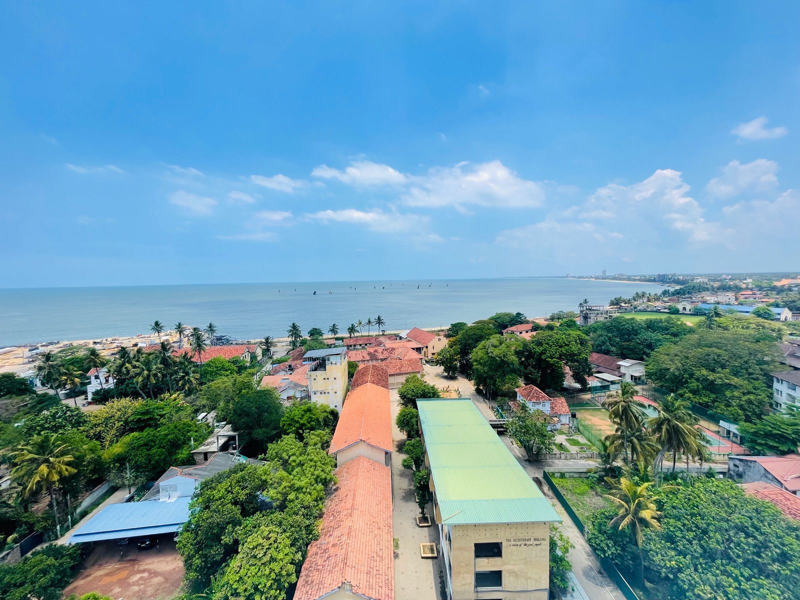 A coastal town with buildings, a beach, and a clear sky.
