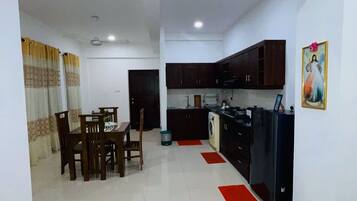 A spacious living area with a dining table and chairs, a kitchen with dark cabinets, and a red rug.