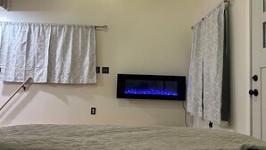 A bedroom with a bed, a wall-mounted TV, and two curtains.