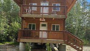 A two-story wooden cabin with a balcony on the upper floor, a staircase leading to the entrance, and a sign that reads "Sky Dipper."