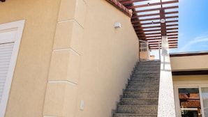 A staircase leading to a covered outdoor area with a wooden pergola and a clear blue sky. - Bz02 Casa Moderna 250m da praia Geribá (Búzios)