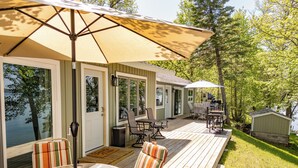 A deck with outdoor furniture, a grill, and a view of a lake.