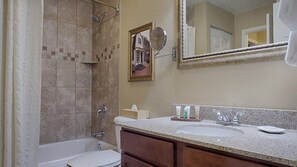 A bathroom with a bathtub, toilet, and sink. There is a framed picture on the wall and a mirror above the sink. - More to do than you will have time for ! (Williamsburg)