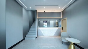 A modern reception area with a staircase, a reception desk, and a seating area with a table. - Dongjing Hotel (Shanghai Shanda College Branch) (Shanghai)